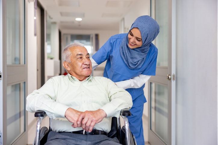 Nurse conversing with senior man at care home whilst thinking about ways to reduce energy consumption